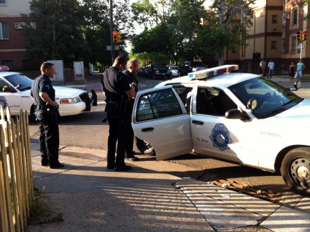 Denver police place the now-handcuffed woman in the back of a cruiser.